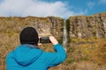 Tourist man taking pictures of Devil`s chimney waterfall, county Sligo, Ireland. Warm sunny day, Cloudy sky. Travel and outdoor