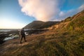 Happy tourist man walk and hike on ocean trail near mountains at sunset time Royalty Free Stock Photo