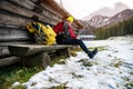 A tourist in a yellow cap and a red down jacket put on crampons for shoes.