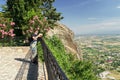 a tourist in a mask on the observation deck takes pictures of a scenic view of the Kalabaka town on top of the cliff