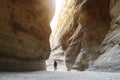 Tourist in narrow passage of rocks of Petra canyon in Jordan. UNESCO World Heritage Site. Way through Siq gorge to stone city Royalty Free Stock Photo