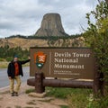 A tourist next the sign of Devils Tower National Monument in Wyoming