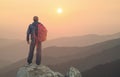 Tourist on the peak of high rocks during sunset