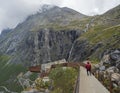 Tourist people at view point platform on Trollstigen or Trolls Path with green valley and waterfall at massif Trolltindene in