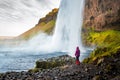 Tourist person in red raincoat watching Seljalandsfoss waterfall in Iceland Royalty Free Stock Photo