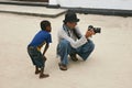 Tourist photographer showing poor boy child photos on camera