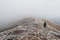 Tourist photographer with tripod on hand walking on frozen hill