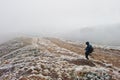 Tourist photographer with tripod on hand walking on frozen hill