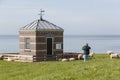 Tourist photographing an Idyllic scenery with sheep, the sea and a traditional building.