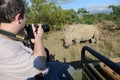 Tourist photographing pair of protected rhinoceros