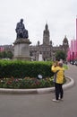 A tourist photographing a statue in George Square in Glasgow, Scotland (UK)