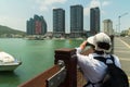Tourist photographs modern skyscrapers on the embankment of the Sanya River in Sanya City on Hainan Island