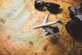 Tourist planning props and travel accessories with airplane, digital camera and sunglasses on old grunge style map desktop. Royalty Free Stock Photo