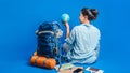 Tourist planning vacation with the help of world map with other travel accessories around. Woman traveler with suitcase on Blue