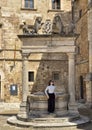 Tourist posing at The well of Griffins and Lions in the big square of Montepulciano, Italy. Royalty Free Stock Photo