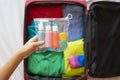 Tourist putting a toiletry bag with liquids in the suitcase.