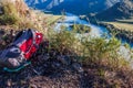Tourist red backpack lying at grass on the edge of river coast Royalty Free Stock Photo
