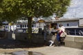 Tourist relax and read on a wall at the waterside of modern Belfast beside the Dutch Barge MV Confiance