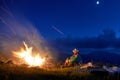 Tourist resting near outdoor bonfire in the night mountains.