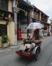 Tourist riding old vintage trishaw or beca around Georgetown