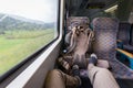 Tourist riding train feet on seat, backpack, rainy weather.