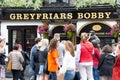 Greyfriars Bobby statue in front of the Pub in Edinburgh touched for luck by tourist