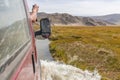 Tourist`s hand leaned out of the car window, photograph the view. Journey of river on SUV car. Mongolia - Altai. photo made from