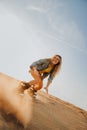 Tourist Sandboarding girl In the Desert Man jumps in and does the trick Royalty Free Stock Photo