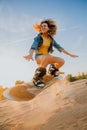 Tourist Sandboarding girl In the Desert Man jumps in and does the trick Royalty Free Stock Photo