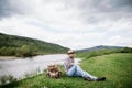 The tourist sat down to rest on the banks of a mountain river after a difficult and long hiking route in the mountains