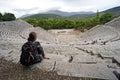 A tourist seats on the highest row of the theatre of Epidauros Royalty Free Stock Photo