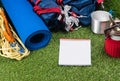 Tourist set on a green lawn for a hike in an expedition, with utensils for cooking food outdoors, with a place for writing, on a w