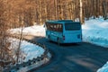 Tourist shuttle bus on the road through wooded landscape in winter Royalty Free Stock Photo