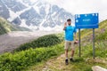 A tourist is standing by a sign with a stop sign