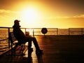 Tourist sit on wharf bench and enjoy misty sunny morning at sea. Smooth water