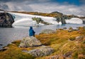 Tourist sits on a rock among the lake. Splendid summer view of outskirts of Aurlandsvegen