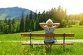 Tourist sitting on a bench overlooking the mount Grosser Arber, Germany.