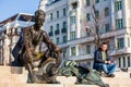 Tourist at the sitting statue of the Hungarian poet Attila Jozsef near the parliament in Budapest