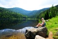 Tourist sitting on stone by moraine lake Kleiner Arbersee, Germany.