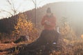 Tourist sitting on a stump eating porridge at sunrise. A hiker is enlightened by the morning sun and enjoys the view. Beskydy