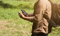 Tourist with smartphone and battery charger is looking for the way in summer forest. Guy with powerbank is lost in the nature.