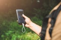 Tourist with smartphone and battery charger is looking for the way in summer forest. Guy with powerbank is lost in the nature.