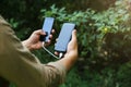 Tourist with smartphone and battery charger is walking in the summer forest. Guy with powerbank is lost in the nature. Modern