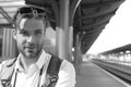 Tourist with smiling face and backpack, copy space. Missed train and travelling concept. Young man standing on platform Royalty Free Stock Photo