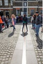 Tourist stand between east and west of prime meridian line in Royal Observatory Greenwich . Greenwich is notable for its name to t