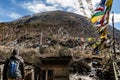 Tourist stand in the front of outdoor toilet with Tibetan prayer flags with Black mountain with snow on the top is background.