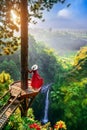 Tourist standing at Air Terjun Kedung Kayang waterfall at sunrise, Indonesia