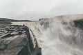 Tourist standing on extremely dangerous distance near Dettifoss waterfall in VatnajÃÂ¶kull National Park in Northeast Iceland