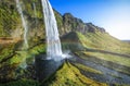 Tourist standing in front of Seljalandsfoss with rainbow around , beautiful amazing landscape from Iceland, Royalty Free Stock Photo