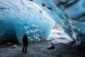 A tourist is standing in an icy, crystal clear cave